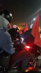 Motorbike riders carrying Vietnamese flags at night