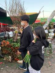 Two people carrying flowers at a market