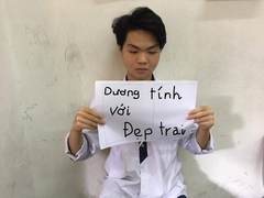 A student holding a handwritten joke about being handsome