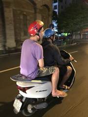 Two friends riding a scooter at night