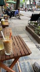 Iced coffee on a wooden table beside a Hanoi street