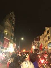 A crowd of motorbike riders carrying Vietnamese flags at night
